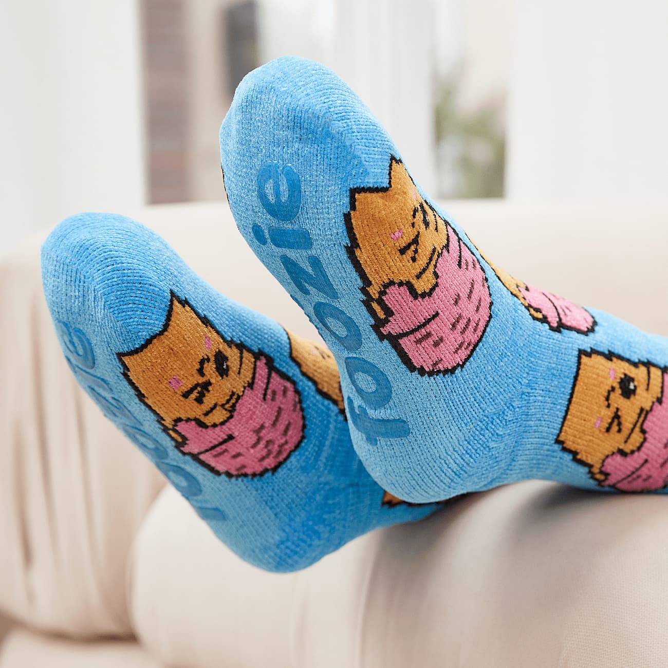 The Foozie™ Ice Cream slipper socks, feet up on the sofa, soles showing the foozie grips