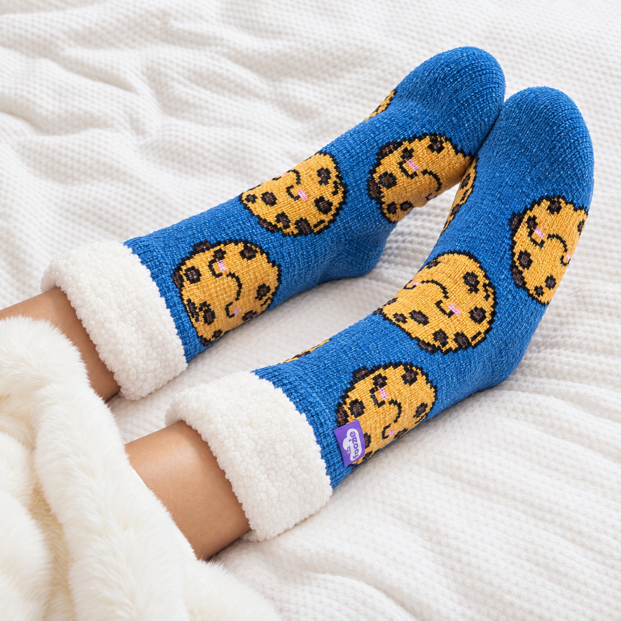 The Foozie™ Cookie slipper socks, under a blanket